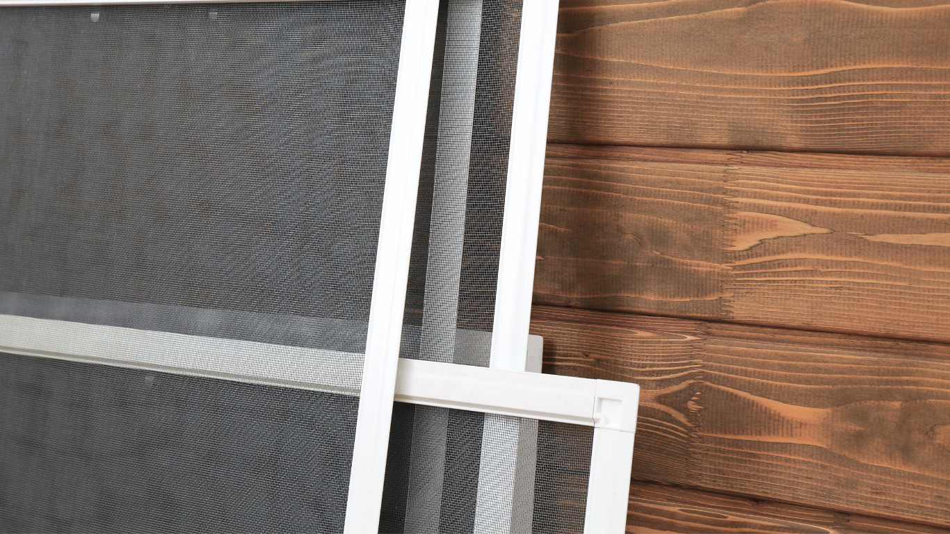 Three rectangular window insect screens with white frames and fine black mesh stacked vertically against a dark wood background.