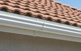 White aluminum fascia board behind a seamless gutter on a Florida home with a terracotta tile roof